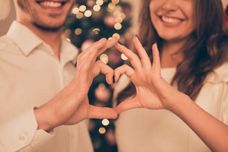 Close up of smiling man and woman making heart with fingersの写真素材