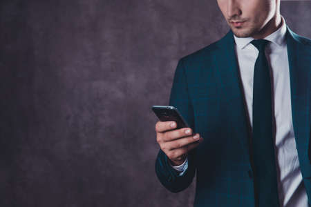 Close up of young businessman in black suit reading message