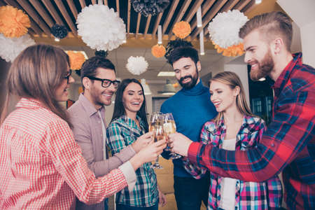 Cheers! six beautiful young happy best friends, boys and girls drink, students laugh and celebrate with champagne and toastの写真素材