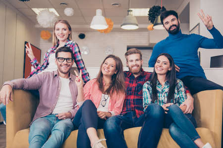 Portrait of six young happy smiling best friends sitting on couchの写真素材