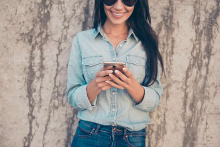 Young cheerful brunette checking her emails on smartphone and using 4g internetの写真素材