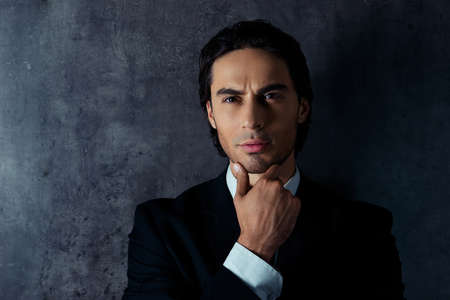 Closeup photo of serious young man in formalwear holding his chin