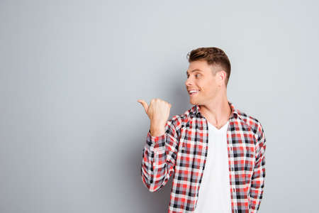 Young cheerful man showing direction on gray backgroundの写真素材