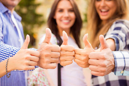 Close up photo of group of happy students showing thumbs up