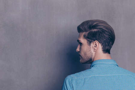 Back view of young modern brunet man on gray backgroundの写真素材