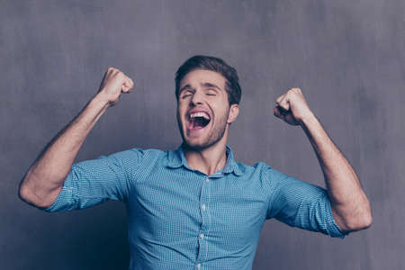 Happy excited guy screaming and showing raised fistsの写真素材