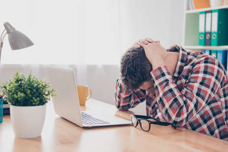 Exhausted overworked young manager with headache lying on tableの写真素材