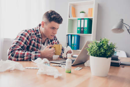 Sick unhappy man with grippe working with laptop in officeの写真素材