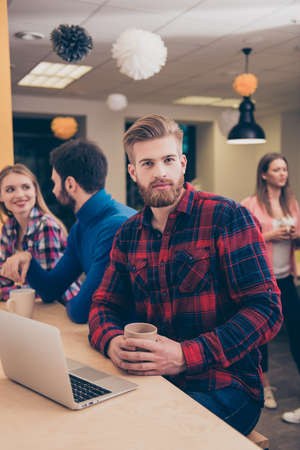 Portrait of young bearded manager with coffee having break on working projectの写真素材
