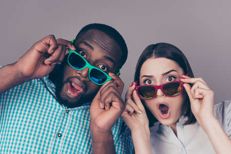 Excited beautyful girl and surprised handsome afro american guy open mouth and holding colored...