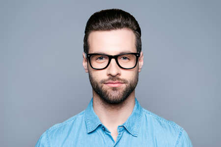 Portrait of handsome young bearded man in glasses on gray background