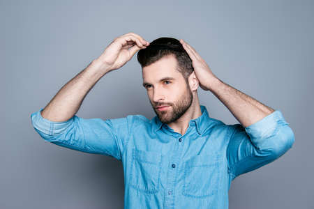 Portrait of handsome young guy combing his hair with fingersの写真素材