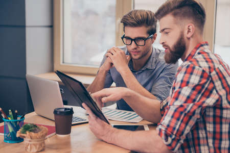 Team of two businessmen discussing new project using tablet in the office