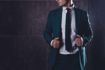 Close up of young businessman touching his black suitの写真素材