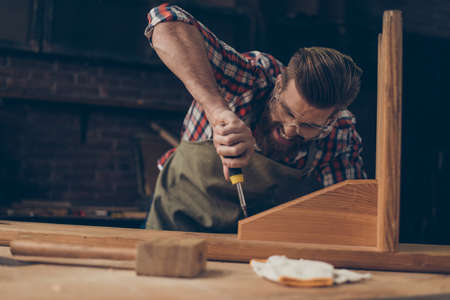 harsh strong worker with screwdriver. Stylish young entrepreneur with brutal hairstyle and saved glasses work at his workplace.の写真素材