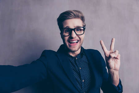 A young happy man taking selfie and showing two fingers upの写真素材