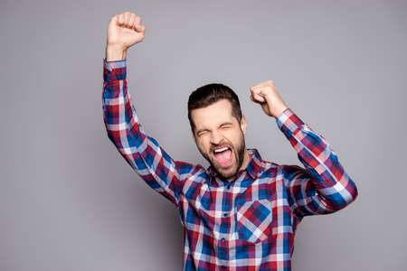 Everything is done! A portrait of successful man yelling with raised hands against gray backgroundの写真素材