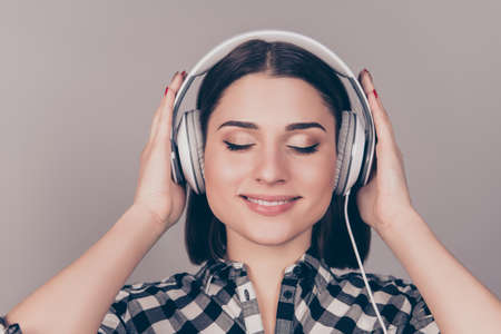 Portrait of young nice-looking woman in headphones with closed eyes listening to music