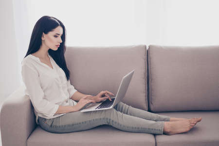 Portrait of beautiful young woman sittin on sofa at home with laptop and smilingの写真素材