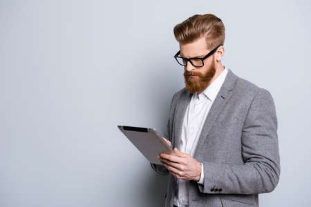 Portrait of serious confident  bearded man in formalwear holding digital tablet and workの写真素材