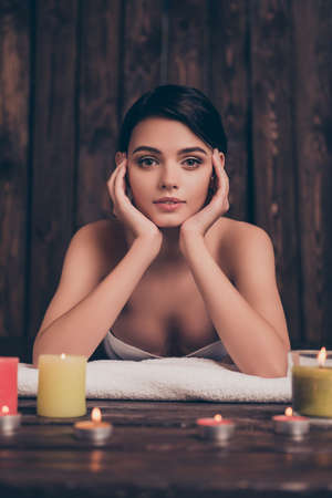 Beautiful relaxed young woman laying in spa salon with candlesの写真素材