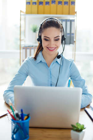 Vertical photo of smiling young pretty woman in headphones working in call center
