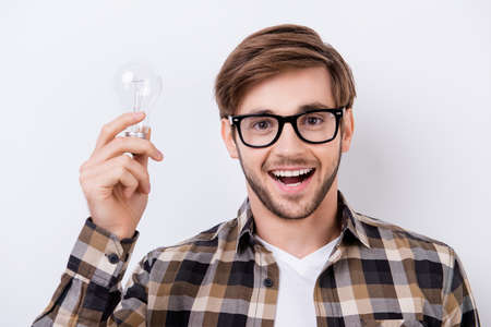 Portrait of young smart man with great idea holding bulb of lamp and excited open mouth