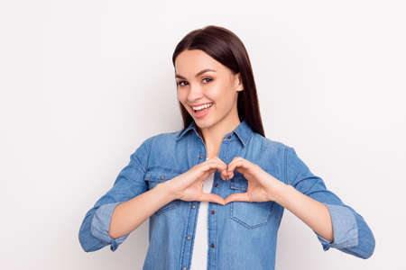 Cute beautiful girl in love making heart with fingers and smilingの写真素材