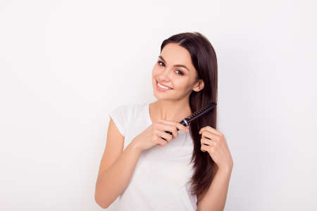 Happy young woman combing her long healthy hair on white backgroundの写真素材
