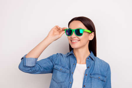 Portrait of young pretty woman in casual jeans shirt touch green glasses and have fun isolated on...