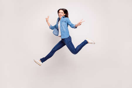 Excited happy pretty  girl in casual jeans clothes high jump with raised hands and legs, on white backgroundの写真素材