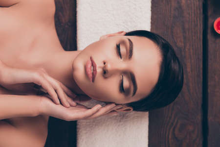 Cute relaxed young woman laying in spa salon with closed eyesの写真素材