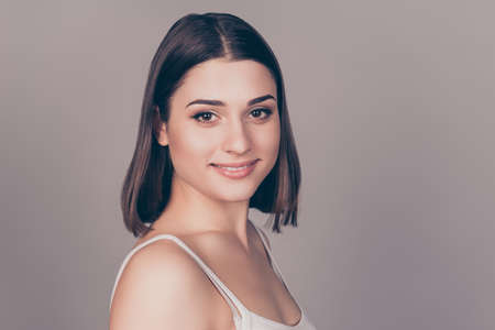 Portrait of young pretty smiling woman against grey background