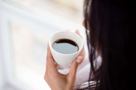 Coffee time! Close up cropped photo of woman drinking hot coffee at bright roomの写真素材