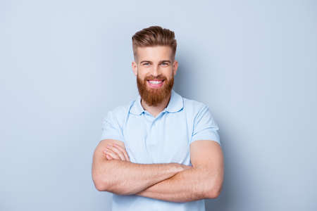 Portrait of smiling young happy bearded man in polo isolated on gray backdropの写真素材