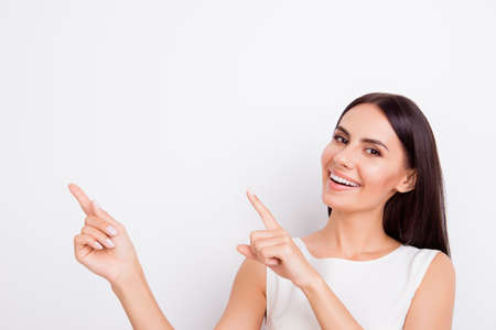 Successful smiling businesslady is pointing up with fingers. She is in isolated on the snow white backgroundの写真素材