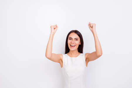 Victory! Excited girl is celebrating success in white smart dress on snow white backgroung. She achieved the goalの写真素材