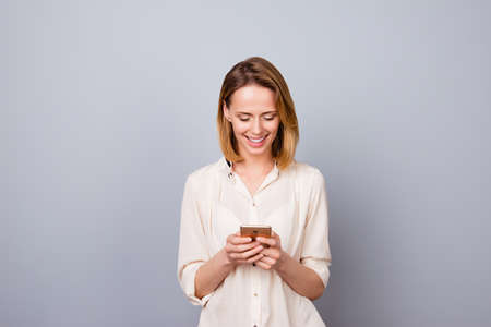 Portrait of cute young smiling woman using smartphone for messagingの写真素材