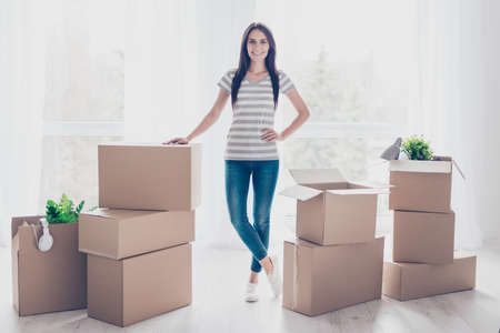 Young pretty lady is moving to new place. She is satisfied, she collected her belongings in boxesの写真素材