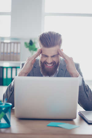 Overworked stressed businessman is having headache and thinking how to end project. He has stylish...