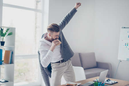Young businessman is having a snack oh his way to meeting. He is very busy, rushing to eat before he goesの写真素材