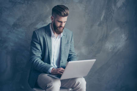 Young confident bearded man using laptop and having online meeting with business investorsの写真素材