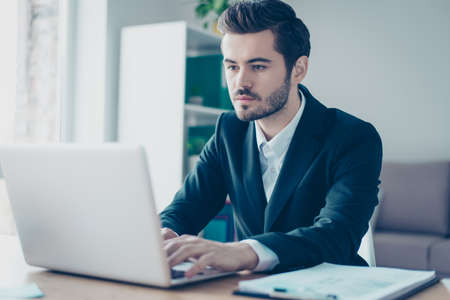 Close up photo of concentrated and confident businessman working with laptop at his office