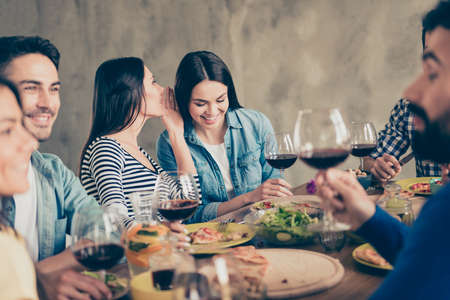Close up of two girls gossipping at the party. Friends are celebrating together with drinks and tasty foodの写真素材
