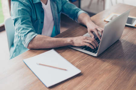Closeup cropped photo of man's hands typing on keyboard a letter on the computer
