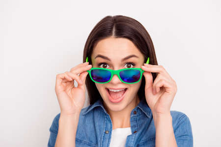 Closeup photo of beautiful funny girl in jeans shirt touching green sunglassesの写真素材