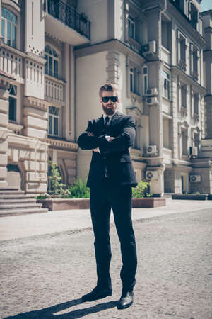 Full size portrait of a harsh agent outdoors. He looks stunning and severe, wearing suit and sunglassesの写真素材