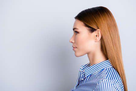 Close up cropped profile portrait of young business lady in striped shirt with serious face on pure background with copy spaceの写真素材