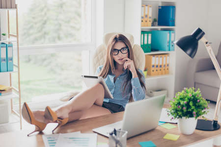 Full size photo of elegant business lady lawyer sitting in her office with attractive legs at the top of table. She is biting her finger and looks so sexyの写真素材