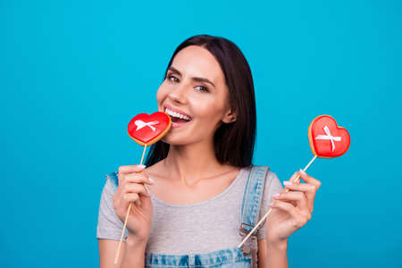Charming young brunette with red candies hearts on bright blue background in casual outfit. So girlish!の写真素材